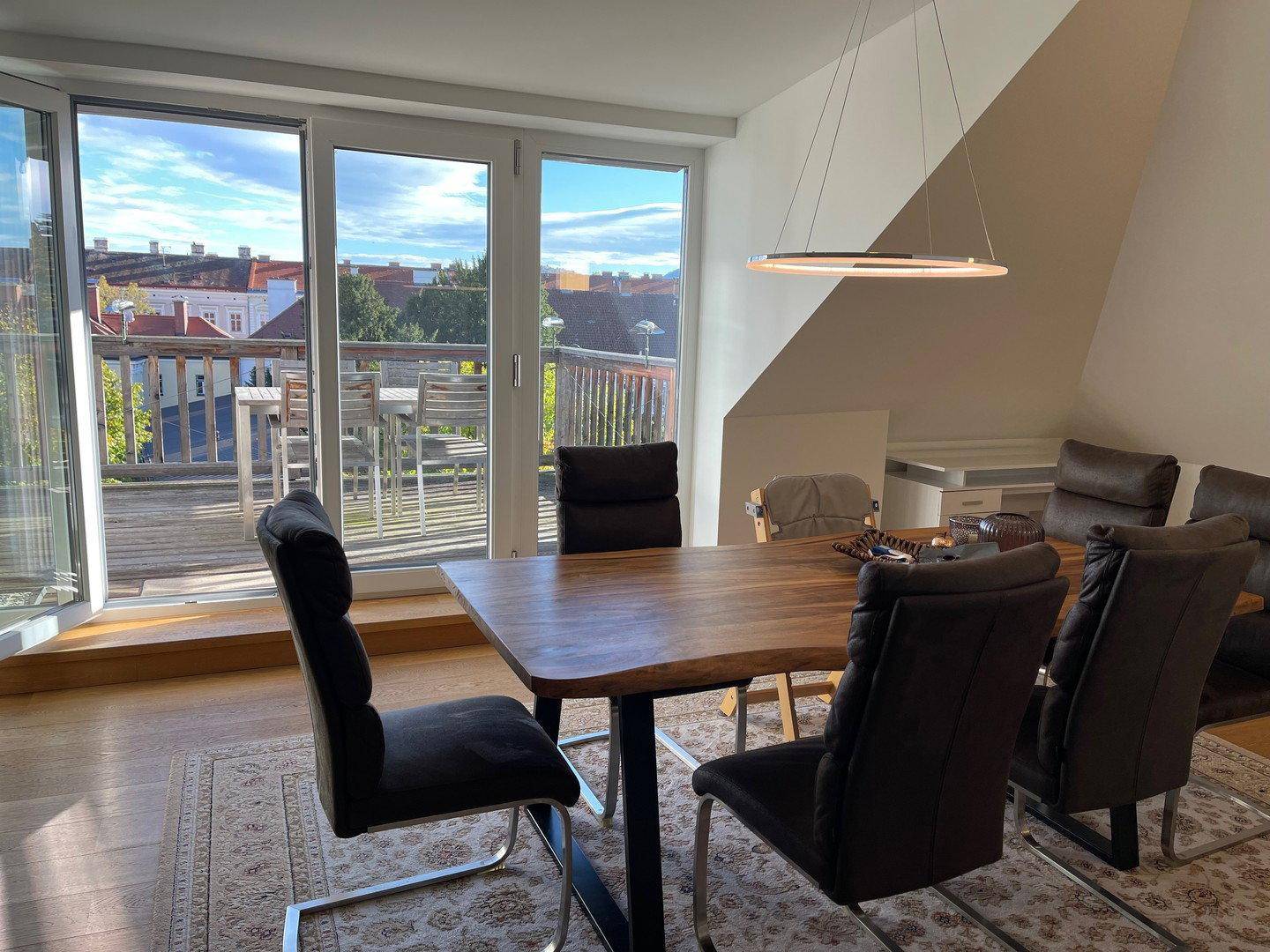Heller Essbereich mit Holztisch und Balkonzugang, bietet einen schönen Ausblick.