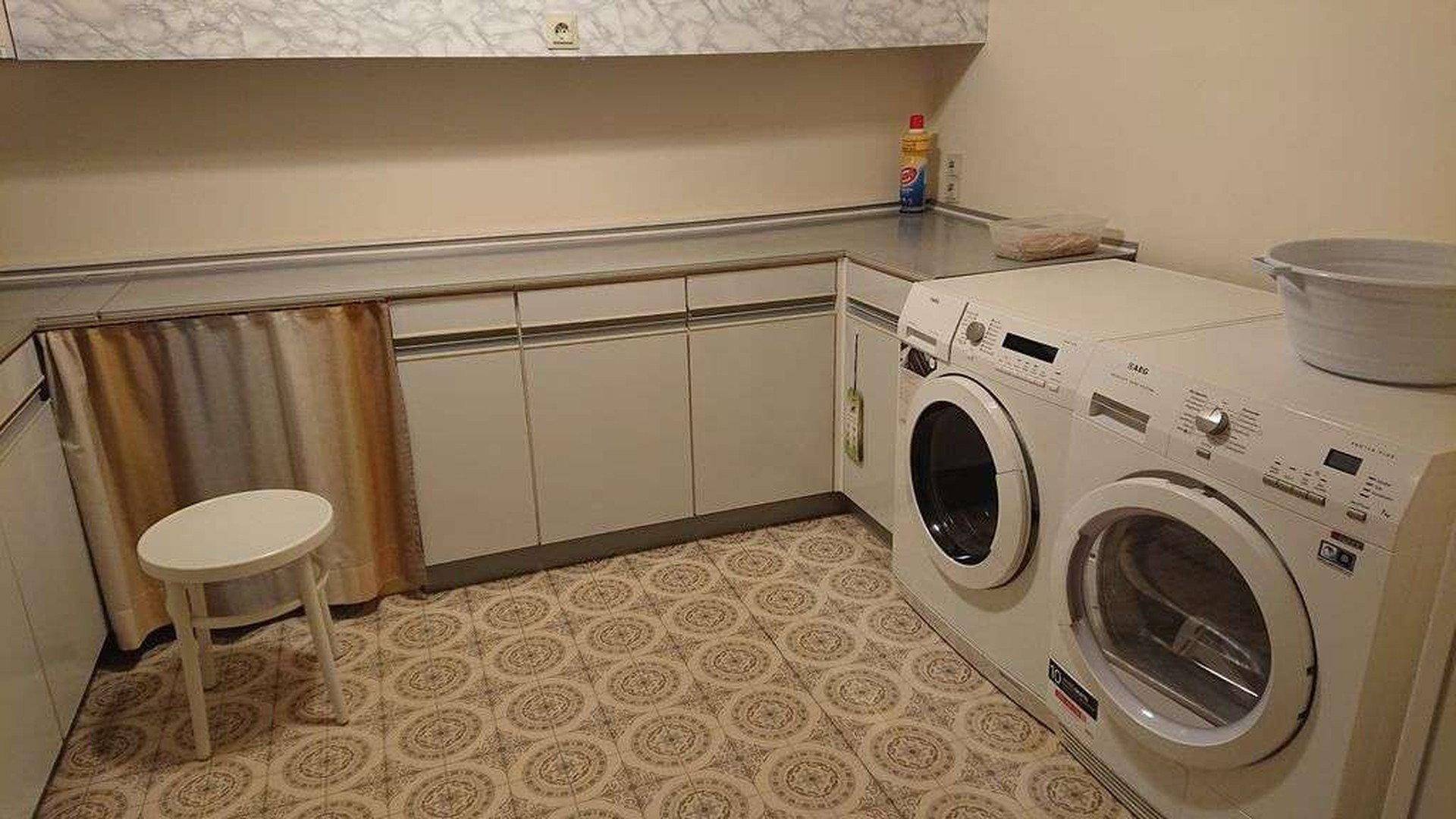 Waschküche mit Waschmaschine, Trockner und Arbeitsplatte.