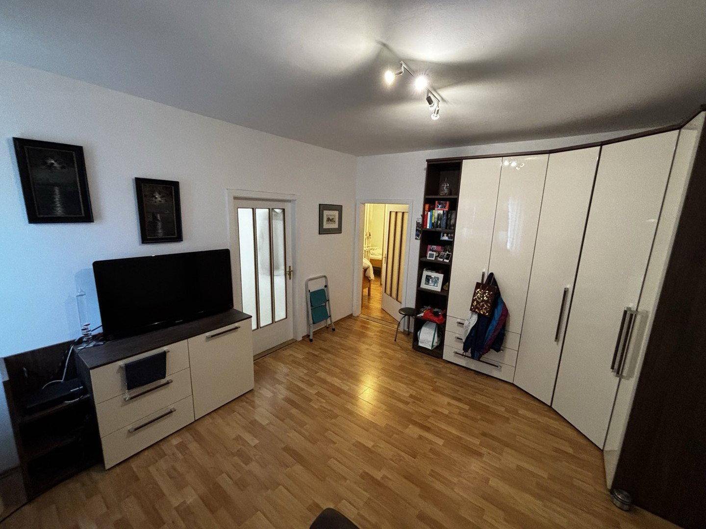 Geräumiger Innenraum mit Holzfußboden, TV-Möbeln und einem großen Kleiderschrank.