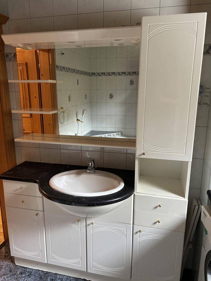 Badezimmer mit weißem Waschtischunterschrank, integriertem Waschbecken und großem Spiegelschrank.