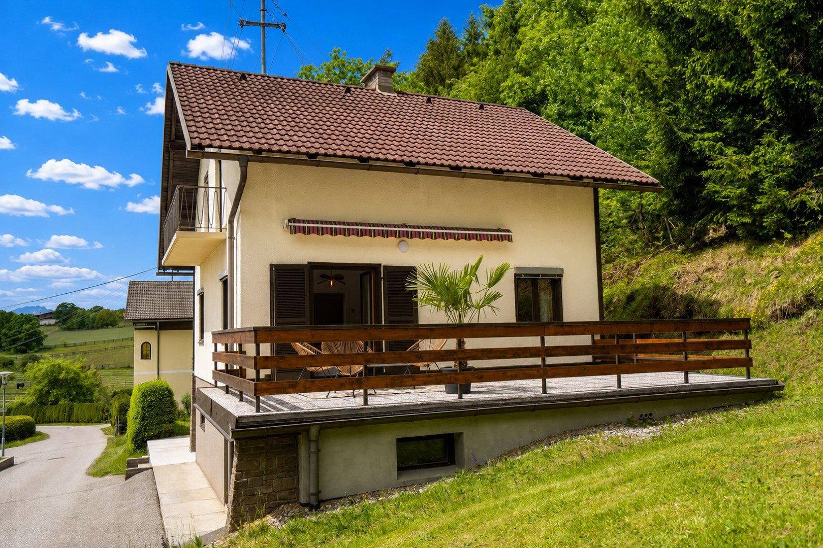 Großzügige Terrasse mit Holzgeländer und Markise, ideal für entspannte Stunden im Freien.
