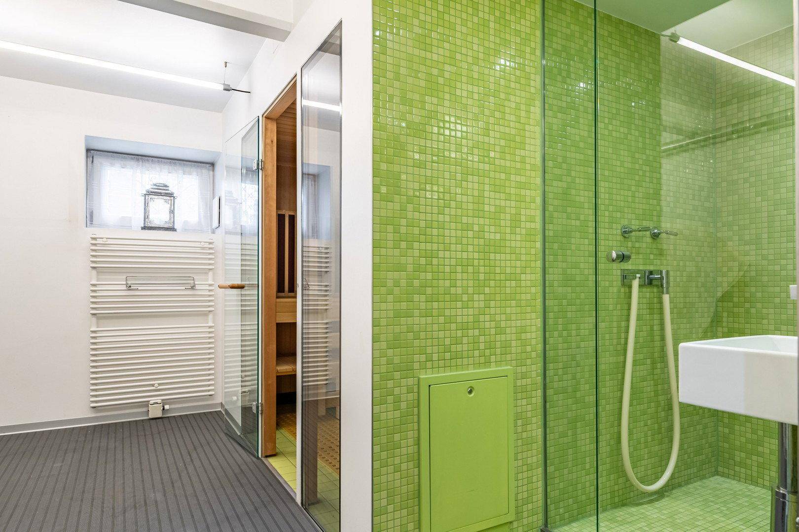 Wellnessbereich mit Sauna, begehbarer Dusche und Handtuchheizkörper in modernem Design.
