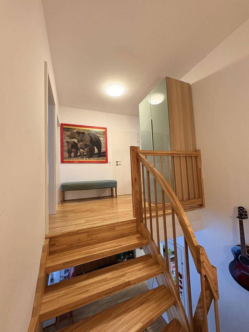Heller Treppenabsatz im Obergeschoss mit Holzgeländer und Parkettboden.