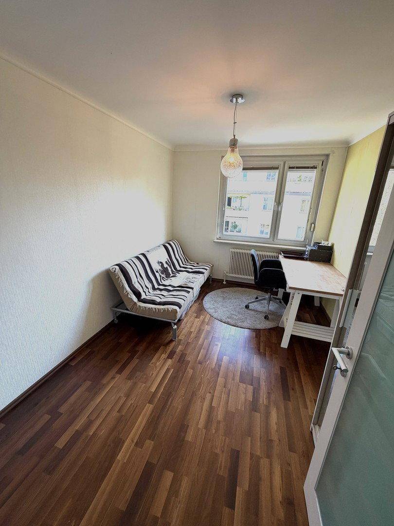 Helles Arbeitszimmer mit Schlafsofa, Schreibtisch und Holzboden, ideal für Gäste oder Home-Office.
