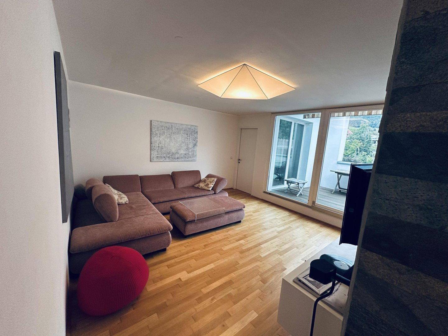 Geräumiges Wohnzimmer mit bequemer Couch, Holzboden und viel natürlichem Licht.