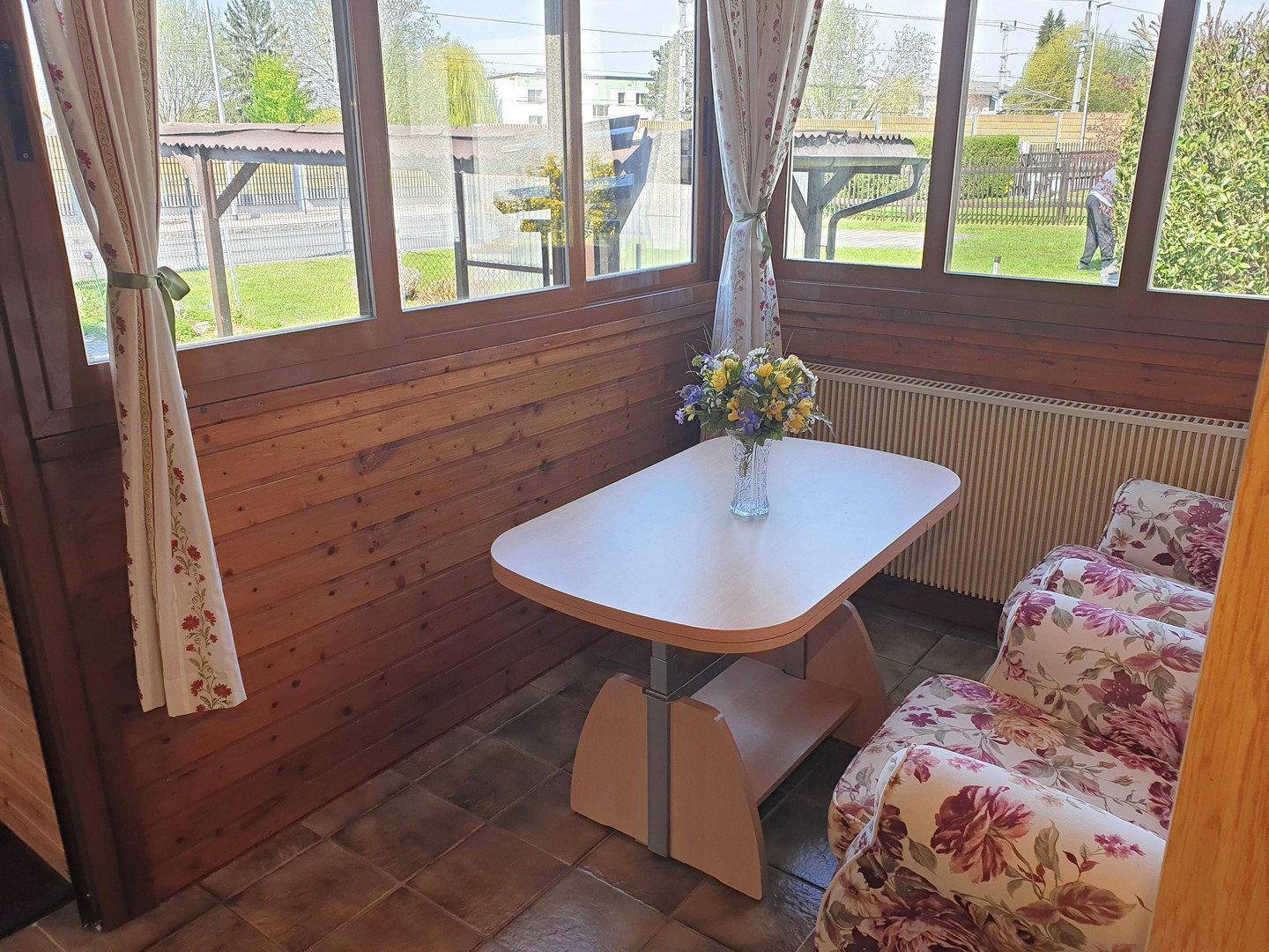 Heller Wohnbereich mit Holzwänden, Fliesenboden und weitem Blick in den Garten.