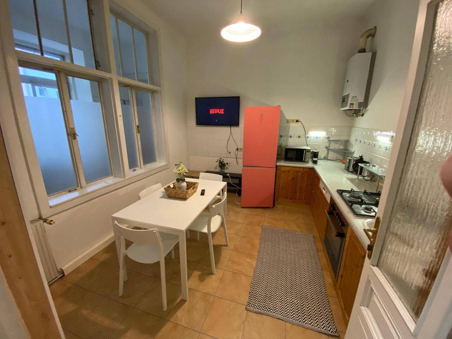 Gemütliche Küche mit Esstisch, Stühlen, einem pinken Kühlschrank und einem Fensterbereich.