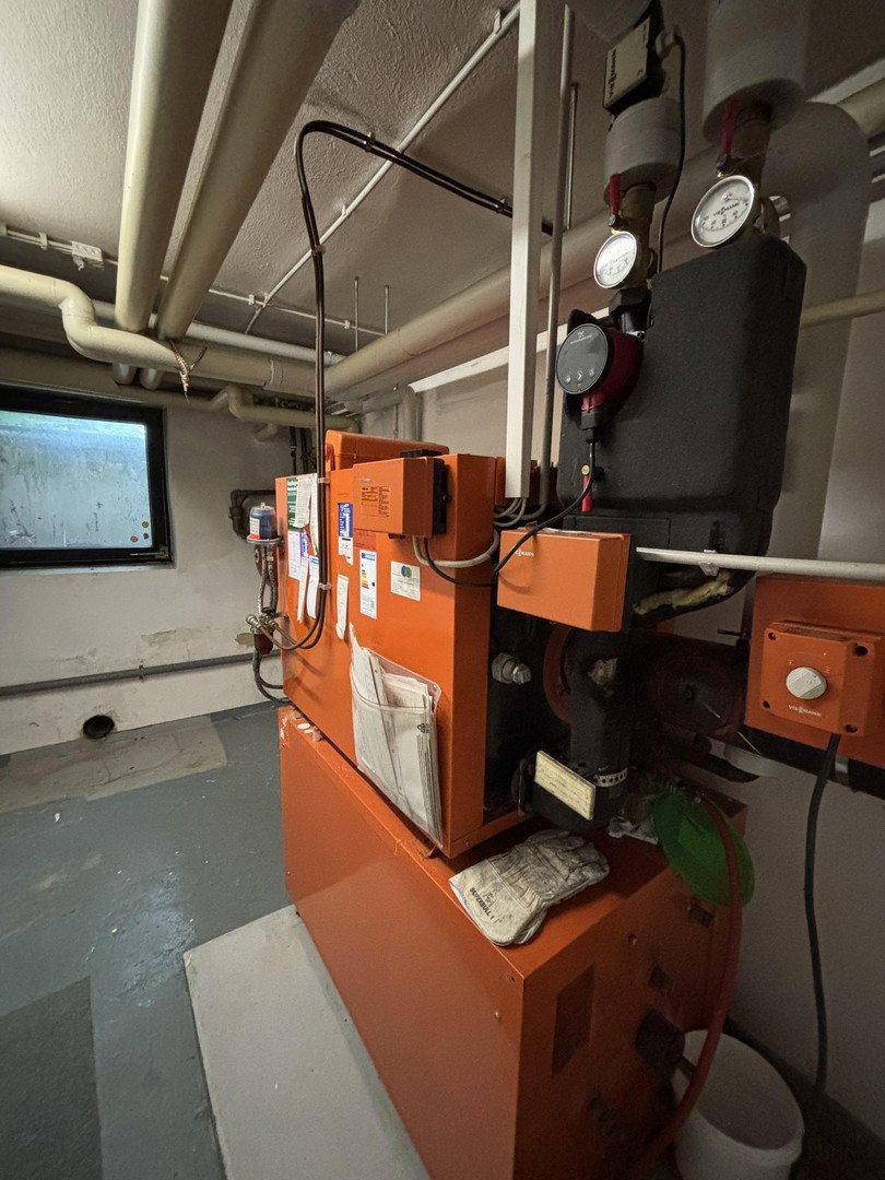 Heizungsanlage mit Rohren und Messgeräten in einem Technikraum im Keller.
