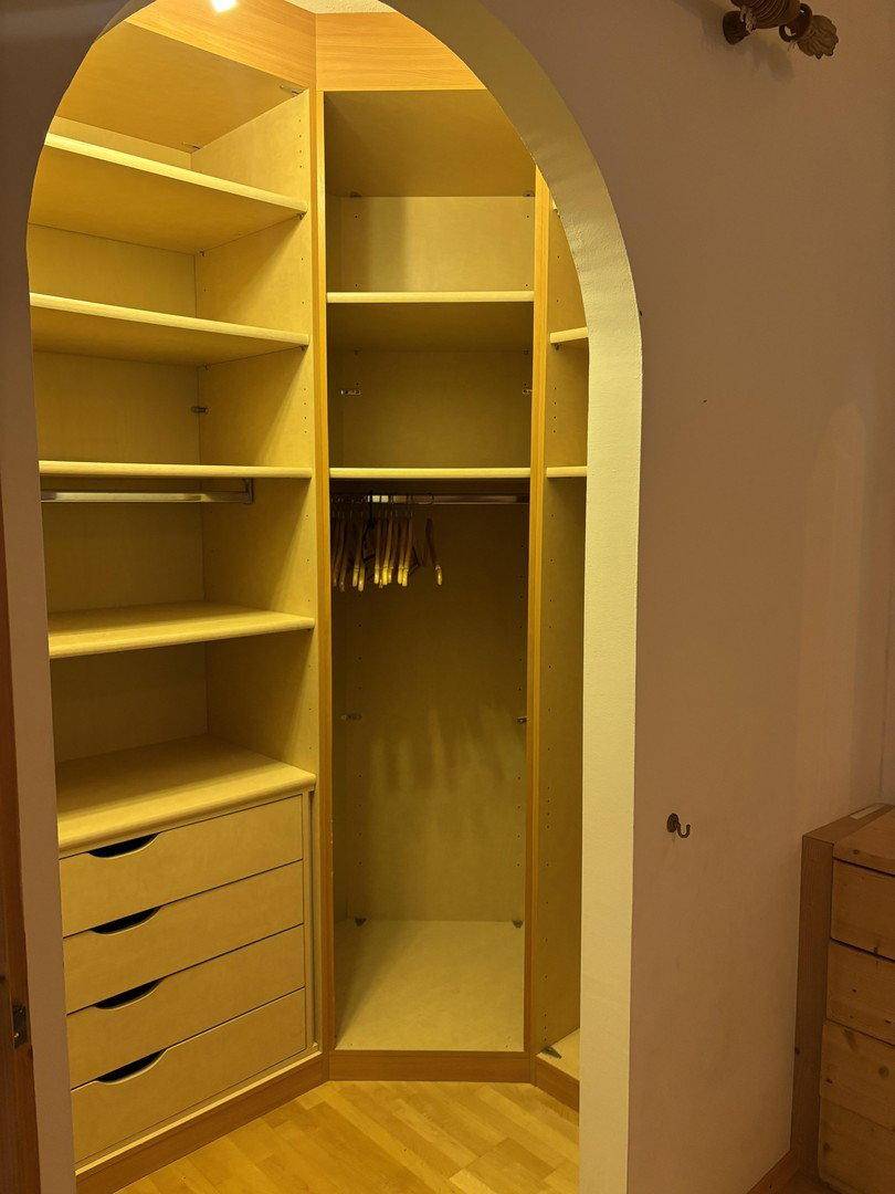 Begehbarer Kleiderschrank mit Regalen und Schubladen, gut beleuchtet und organisiert.