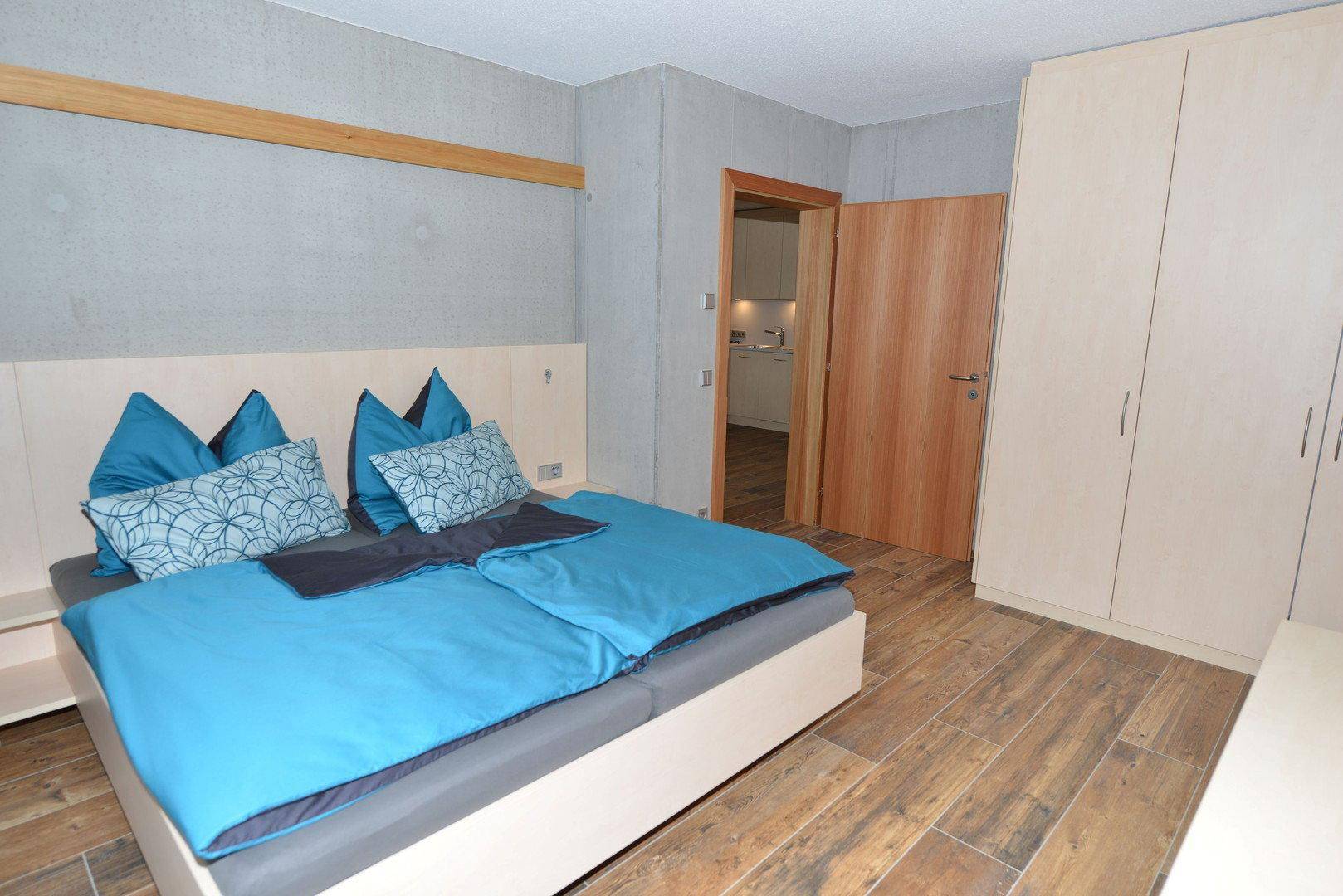 Schlafzimmer mit Doppelbett, Holzboden und Einbauschränken in hellem, modernem Design.