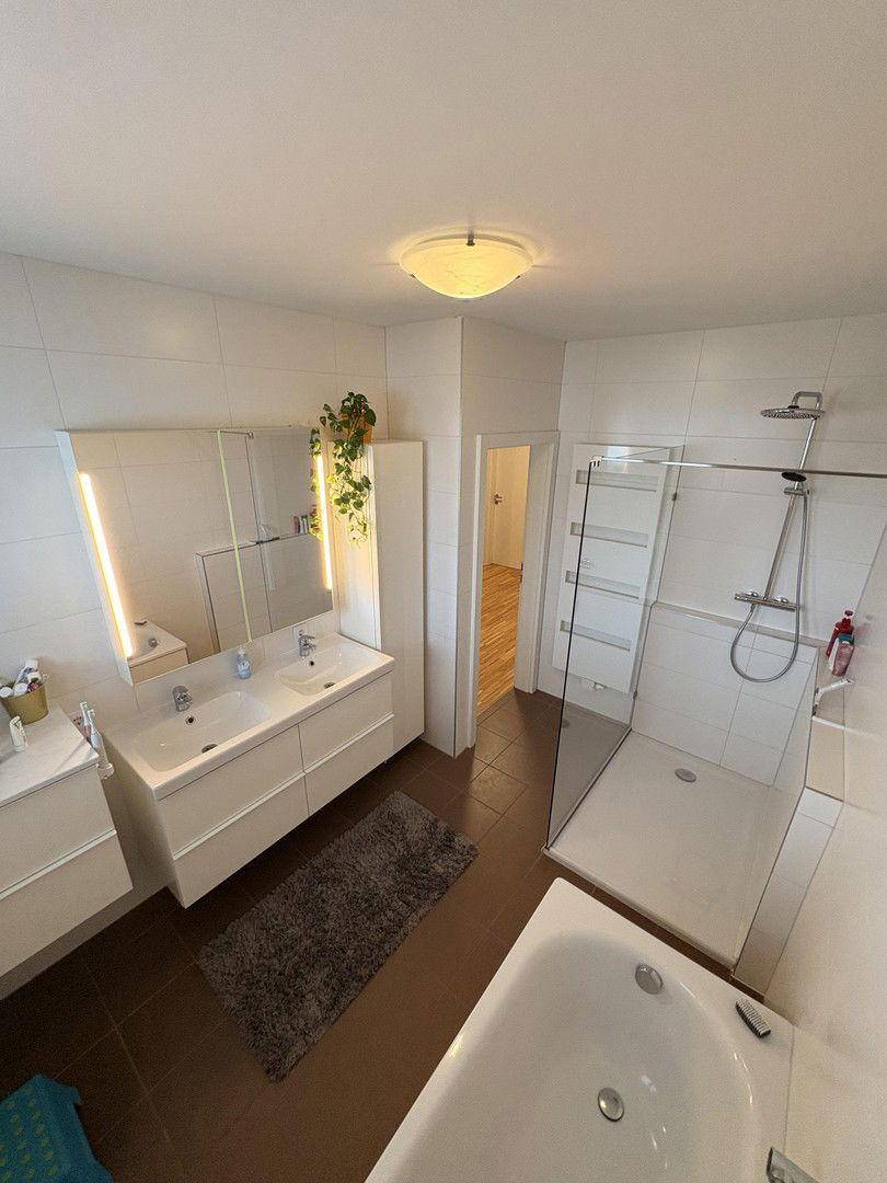 Modernes Badezimmer mit Doppelwaschbecken, großer Dusche und Badewanne.