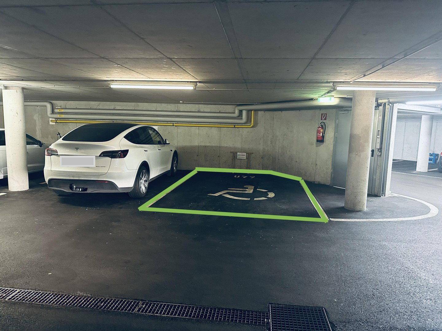 Tiefgaragenstellplatz mit Markierung für barrierefreies Parken und guter Beleuchtung.