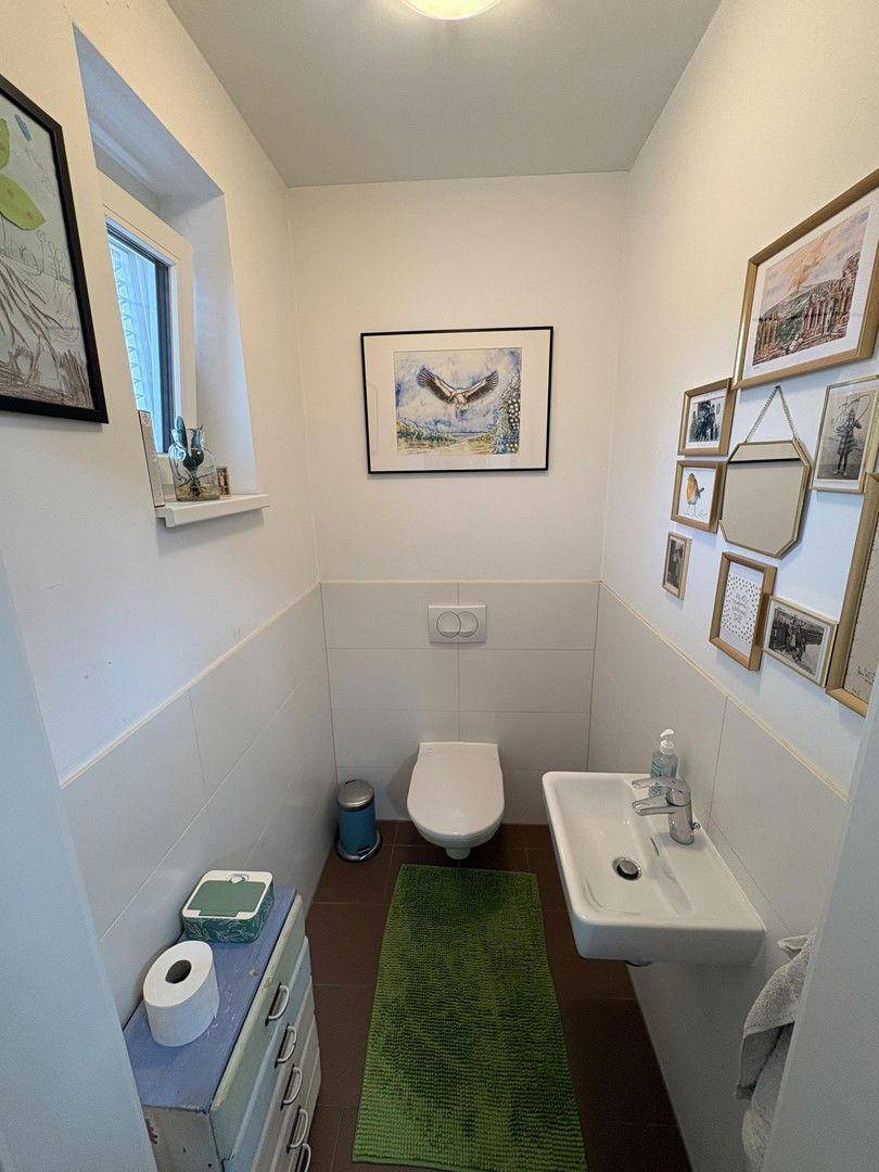 Kleines Gäste-WC mit Fenster, Wand-WC und modernem Waschbecken.