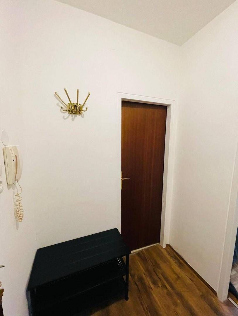 Heller Flur mit Laminatboden, Garderobe und einer dunklen Eingangstür.