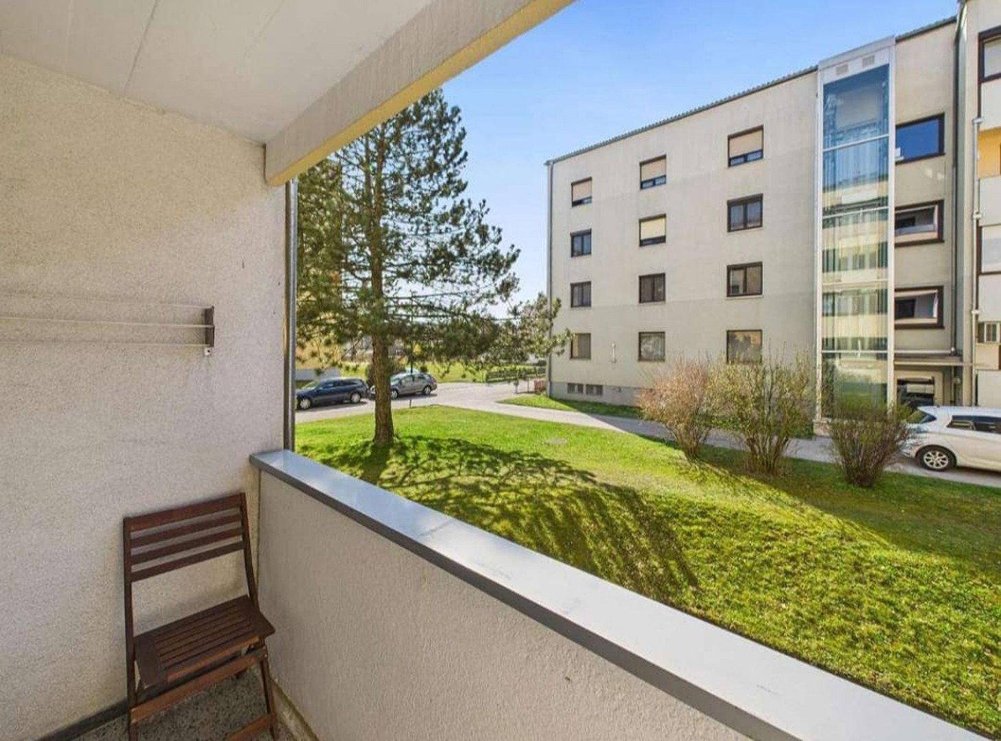 Geräumiger Balkon mit Blick auf eine Grünfläche und die umliegenden Wohngebäude.
