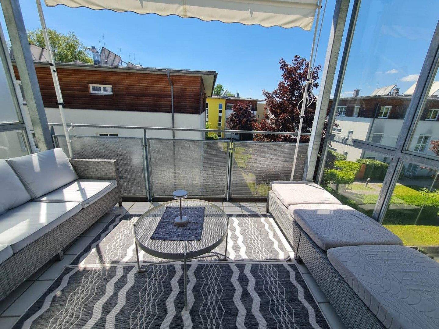 Möblierter Balkon mit Sitzgelegenheiten und Blick auf den grünen Innenhof.