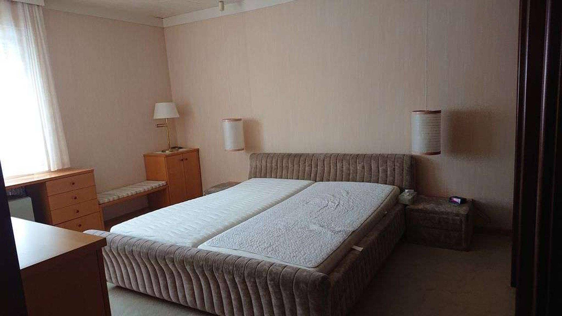 Schlafzimmer mit Doppelbett, Nachttischen und Fenster mit Vorhängen.