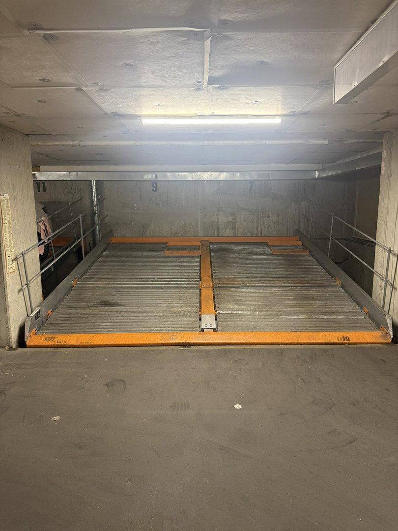 Leere Parkplattform in einer Tiefgarage mit Betonwänden und Decken, bereit für ein Fahrzeug.