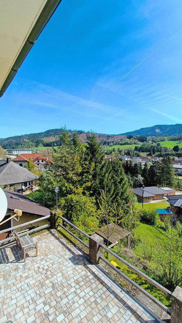 Geräumige geflieste Terrasse mit Holzbalkon und weitem Blick auf die Landschaft.
