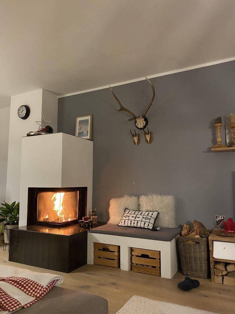 Gemütliches Wohnzimmer mit brennendem Kamin, Sitzbank und alpiner Dekoration.