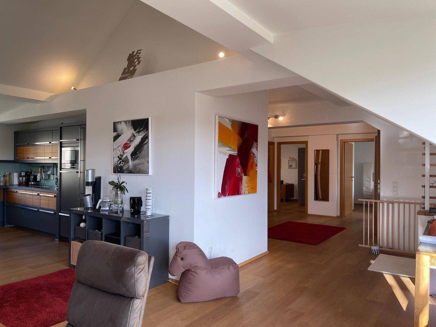 Übergangsbereich zwischen Esszimmer und Flur, mit Holzboden und moderner Kunst an den Wänden.
