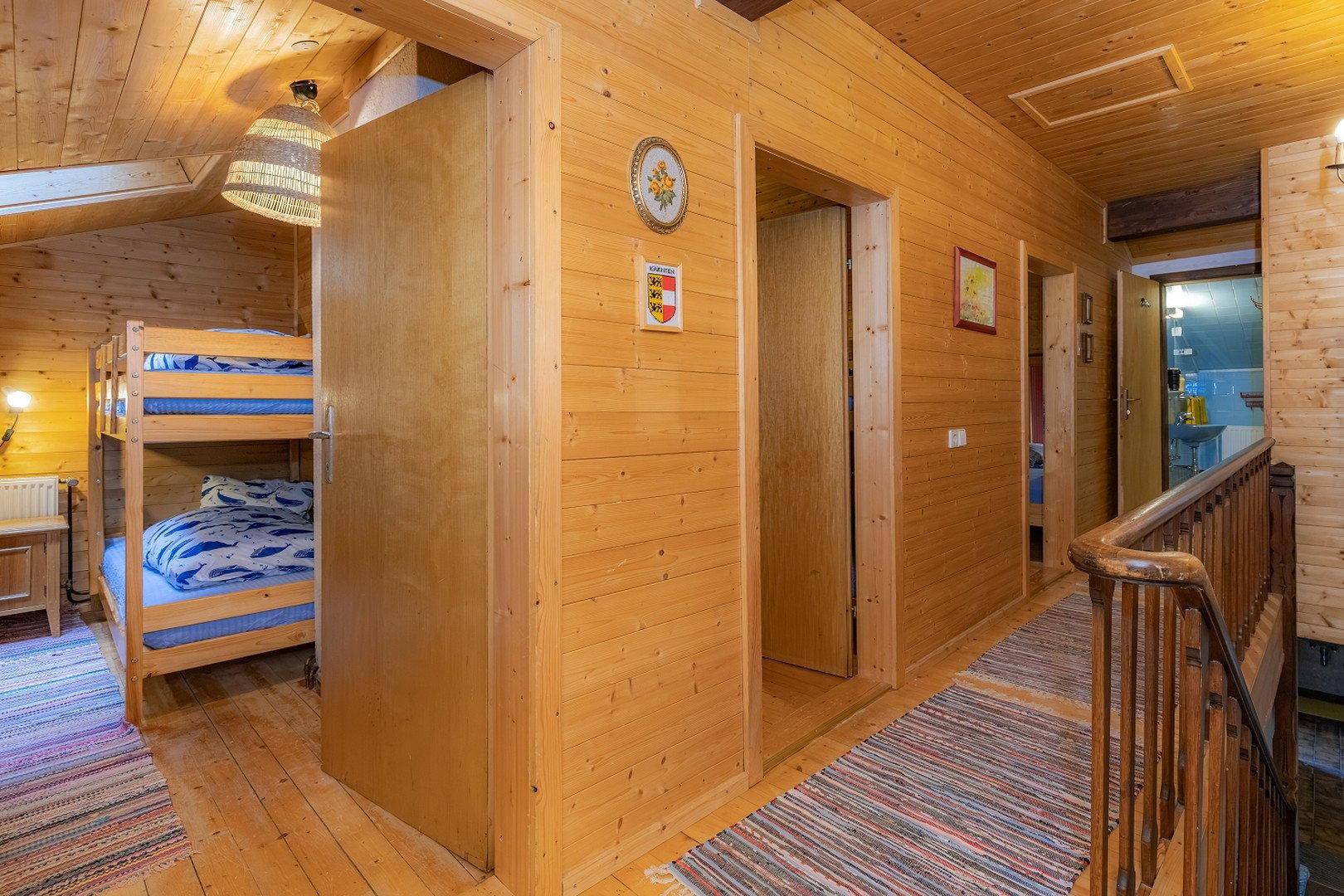 Holzvertäfelter Flur mit Etagenbetten im Hintergrund und einem kleinen Aufzug.