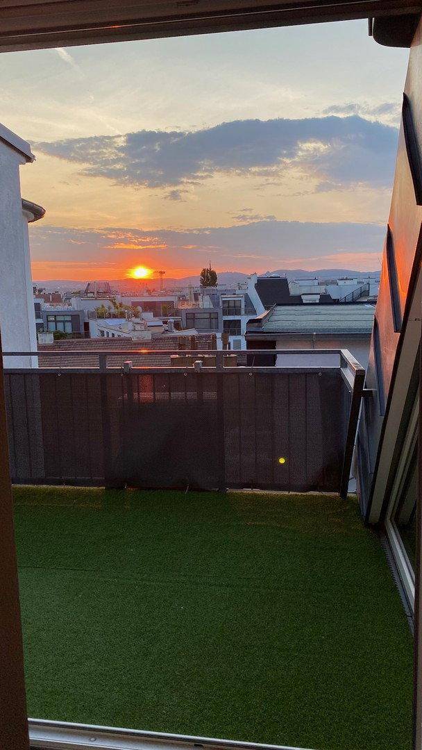 Dachterrasse bei Sonnenuntergang mit Panoramablick über die Dächer der Stadt.