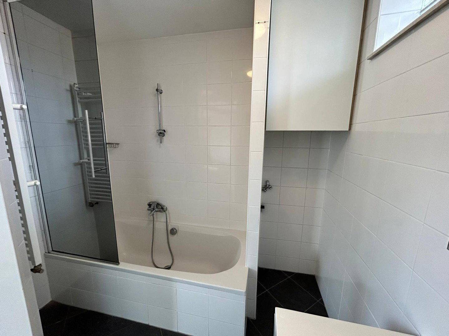 Modernes Badezimmer mit Badewanne, Duschabtrennung und weiß gefliesten Wänden.