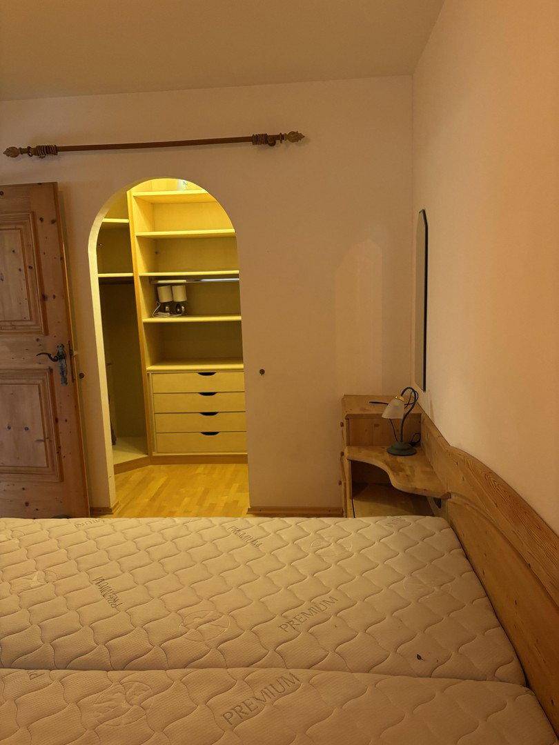 Schlafzimmer mit Blick auf einen begehbaren Kleiderschrank, ausgestattet mit einem Holzbett.