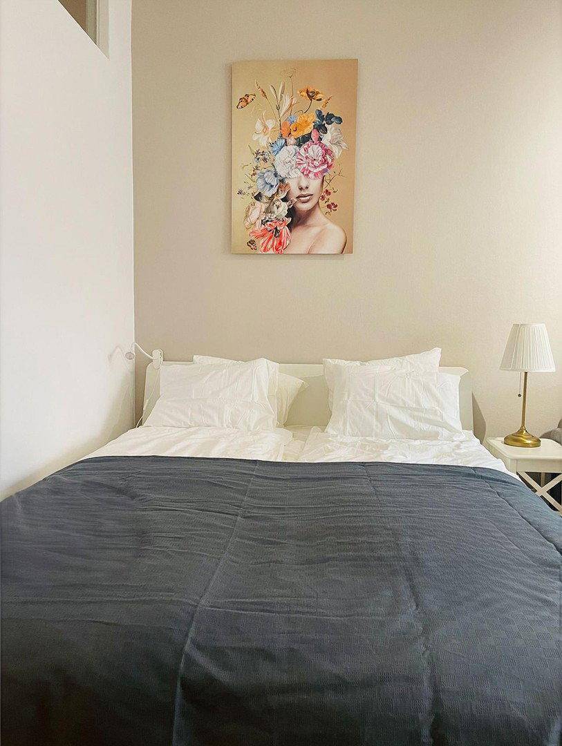 Schlafbereich mit Doppelbett, Nachttischlampe und dekorativem Wandbild.