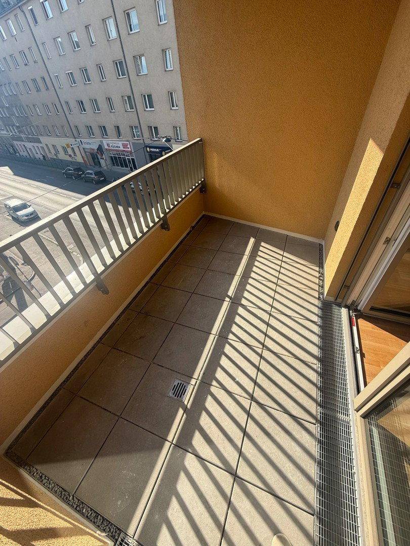 Sonniger Balkon mit Fliesenboden und Blick auf die Straße.