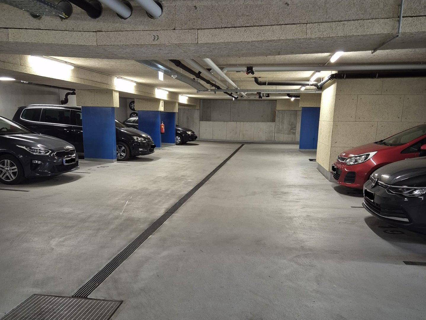 Geräumige Tiefgarage mit mehreren geparkten Fahrzeugen und Betonwänden.