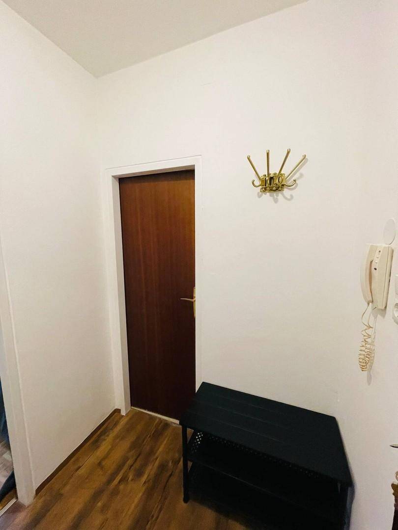 Heller Flur mit Holzboden, Garderobe und Schuhregal, der zu weiteren Räumen führt.