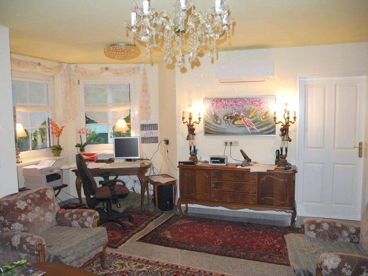Arbeitszimmer mit Schreibtisch, antiken Möbeln, Klimaanlage und Kronleuchter.