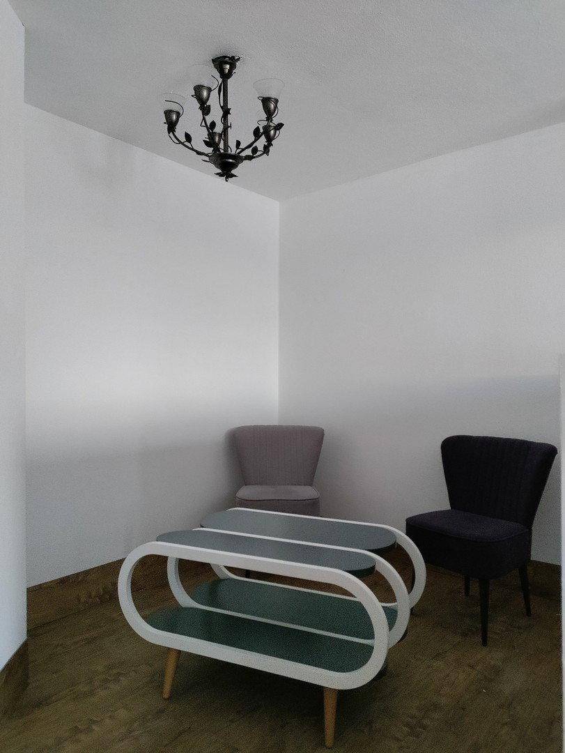 Gemütliche Sitzecke mit zwei Stühlen und einem modernen Couchtisch unter einer Deckenleuchte.