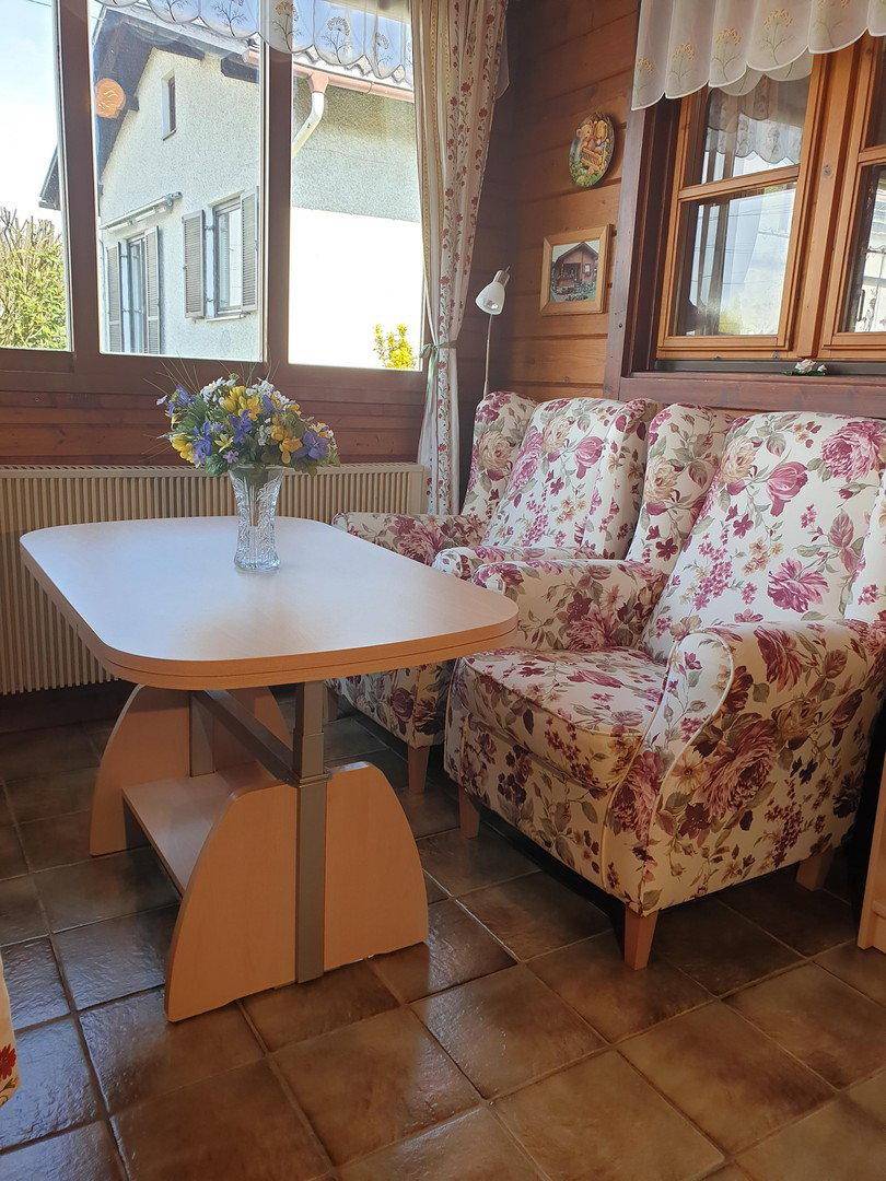 Gemütlicher Wohnbereich mit floral gemusterten Sesseln, Holzwänden und Fliesenboden.