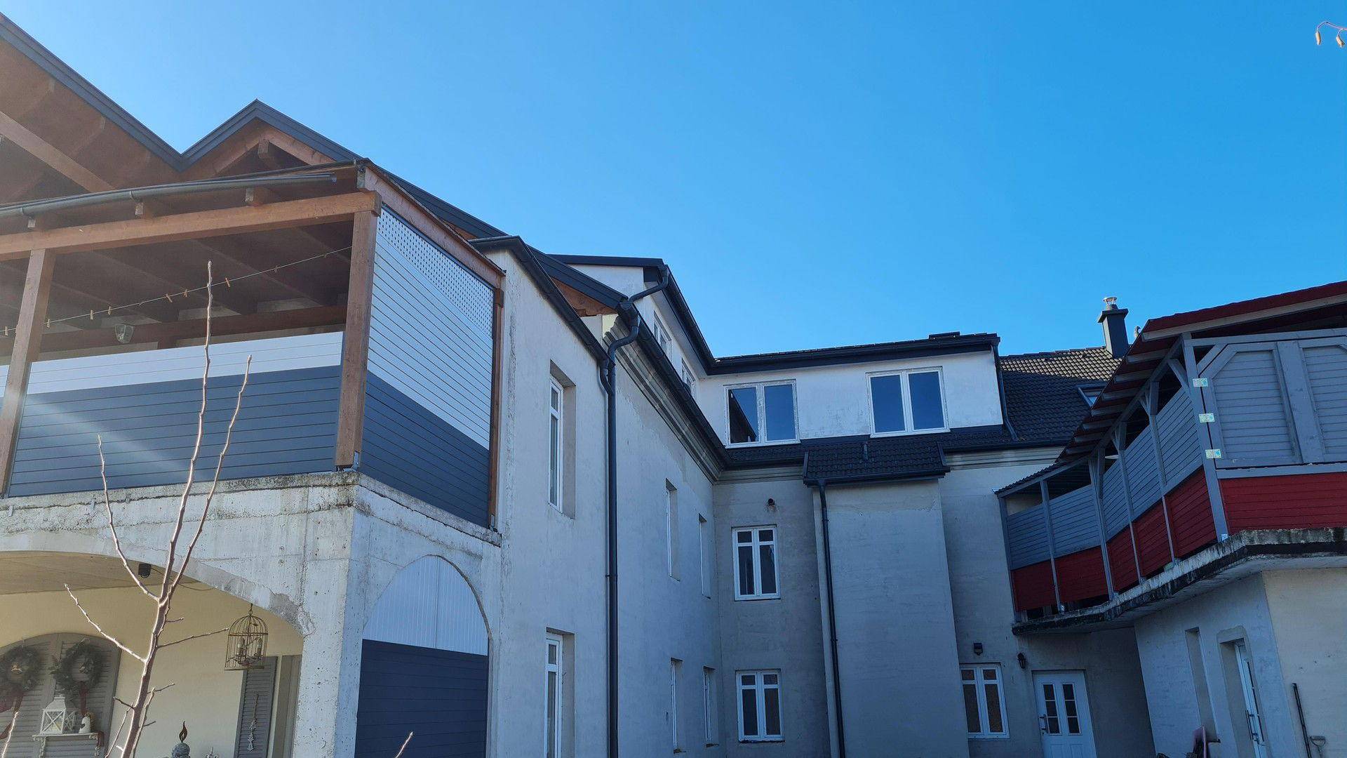 Seitenansicht des Gebäudes mit mehreren Balkonen und großen Fenstern unter klarem blauem Himmel.