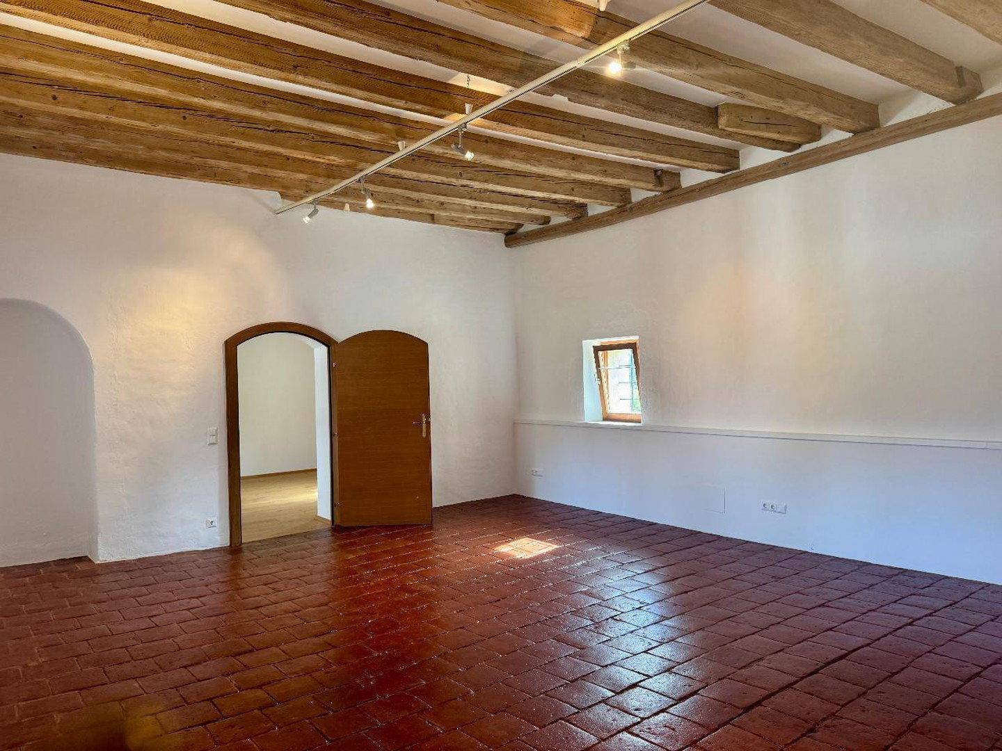 Heller Raum mit rustikalen Holzbalken an der Decke und traditionellem Terrakottaboden.