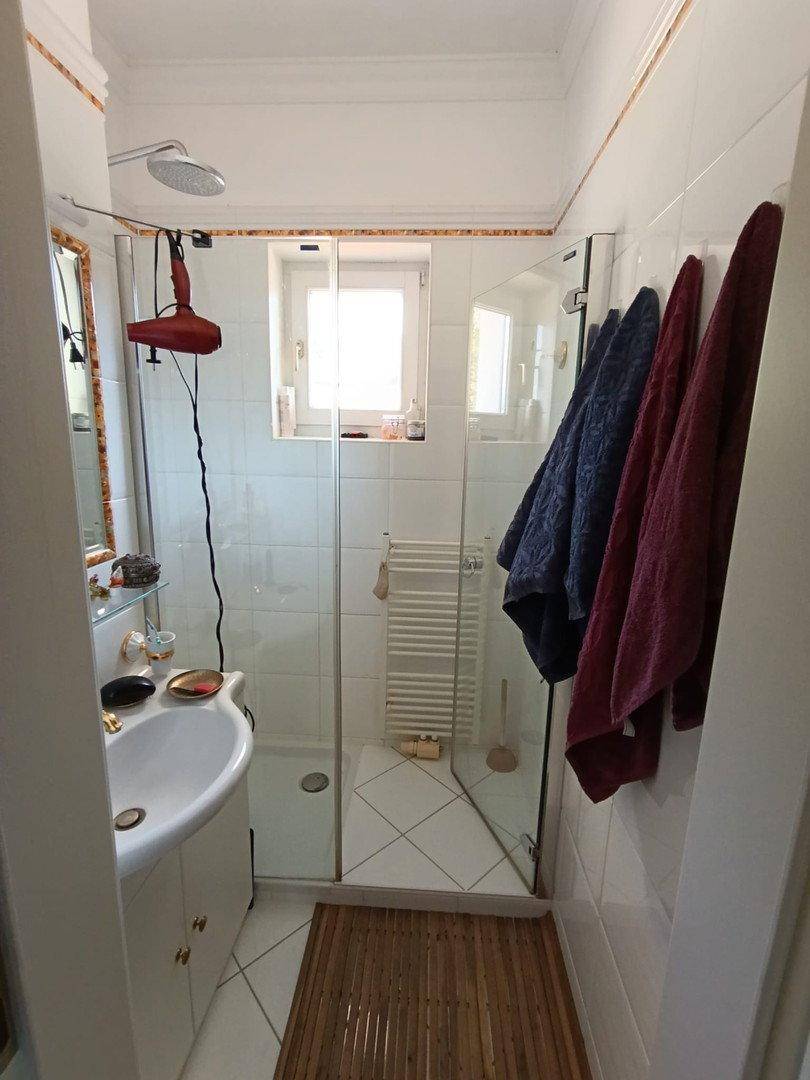 Helles Badezimmer mit Duschkabine, Waschbecken und Fenster, das für gute Belüftung sorgt.