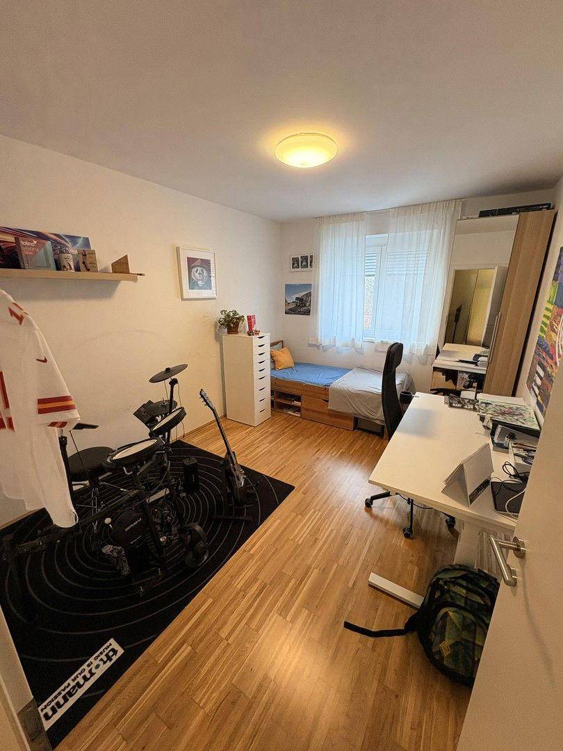 Jugendzimmer mit Holzboden, Schreibtisch und Musikinstrumenten, ideal zum Lernen und Entspannen.