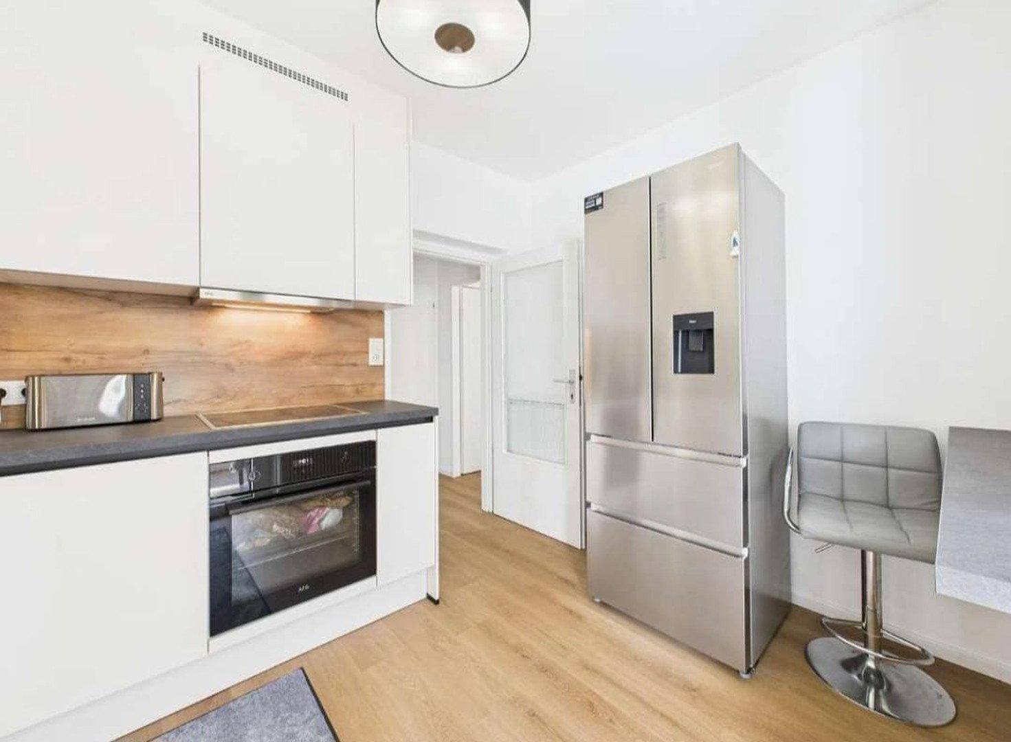 Funktionale Küche mit großem Kühlschrank, Backofen und Bartisch für schnelles Essen.