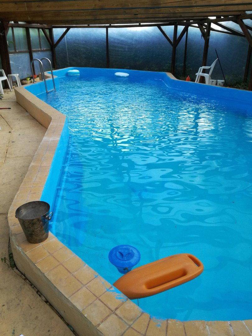 Überdachter Swimmingpool mit blauer Wasseroberfläche und gefliestem Rand.