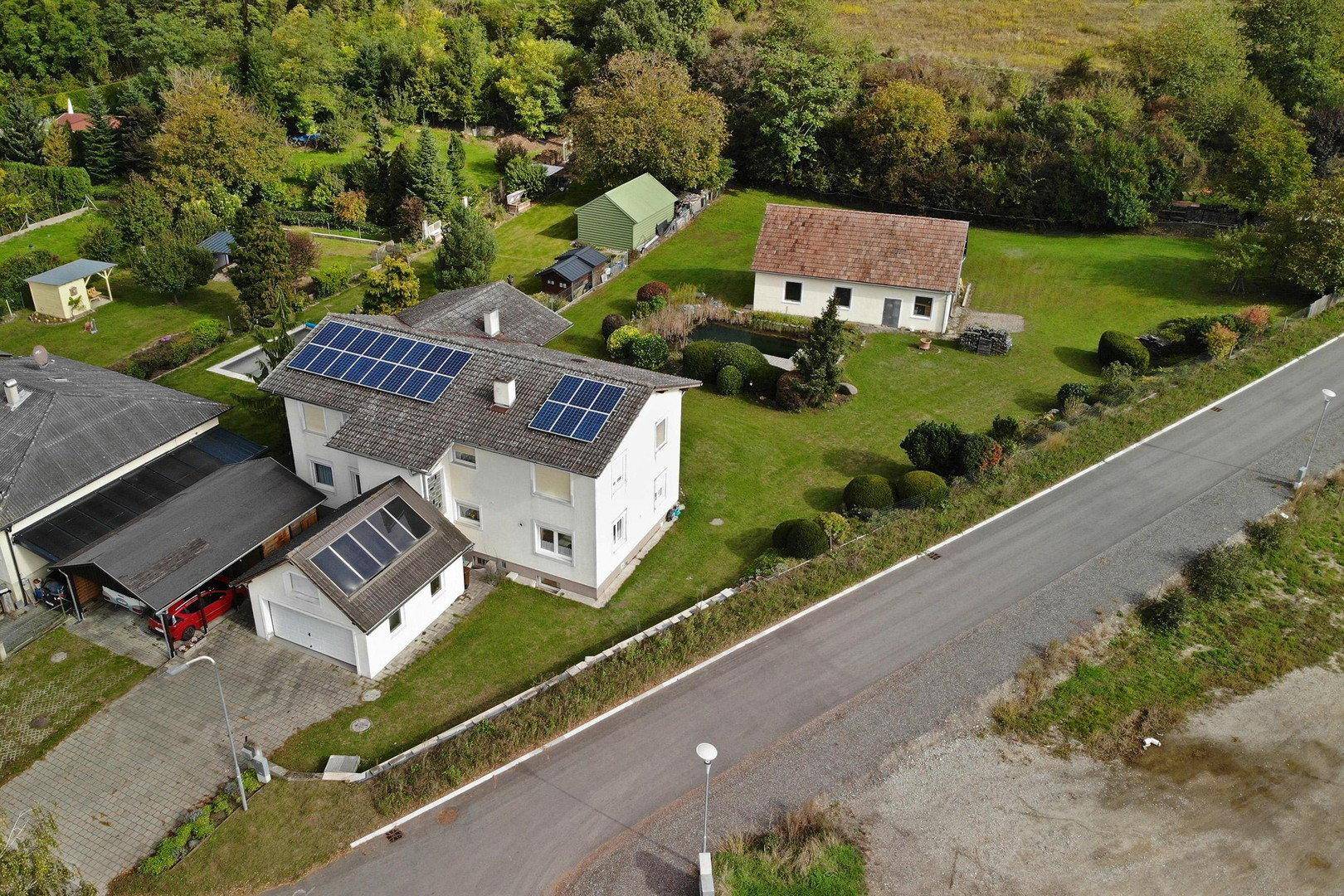 Luftaufnahme des Hauses mit Solaranlage auf dem Dach und großem Gartenbereich.