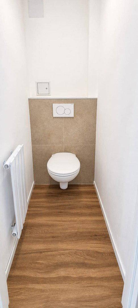 Separates WC mit wandhängender Toilette und modernem Laminatboden, praktisch und funktional.