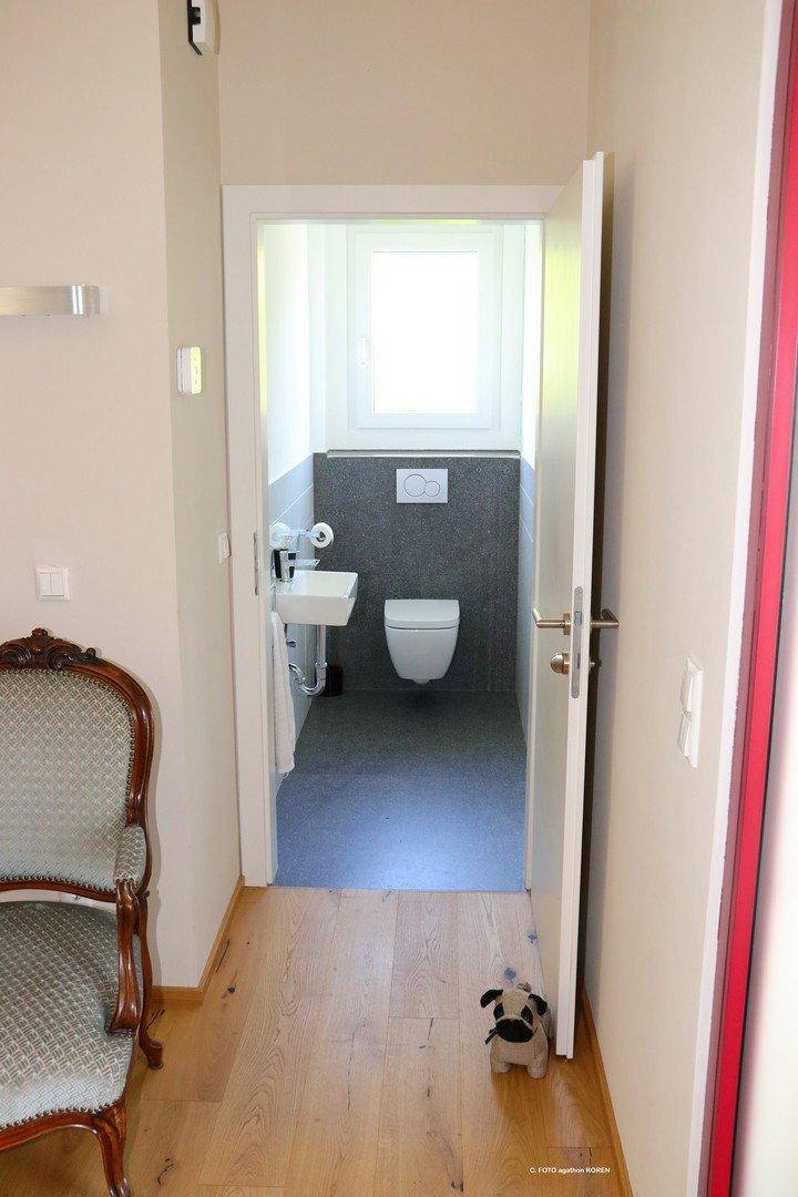 Kleines Gäste-WC mit Fenster, wandhängendem WC und kleinem Waschbecken.