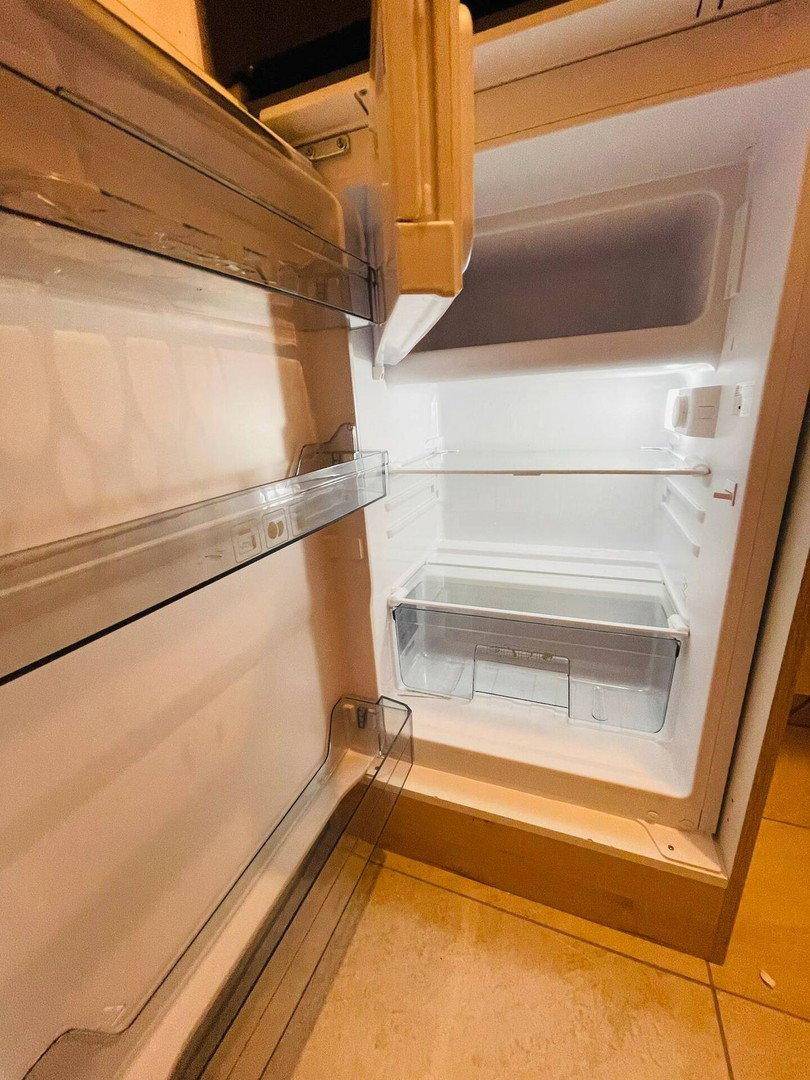 Offener Kühlschrank mit leeren Fächern und einer Gemüseschublade, bereit zur Befüllung.