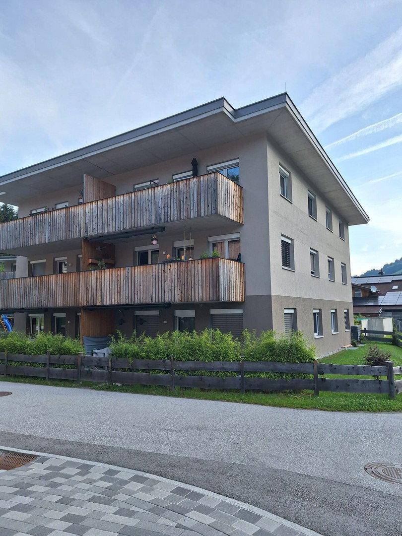 Modernes Mehrfamilienhaus mit Holzverkleidung an den Balkonen und Flachdach.