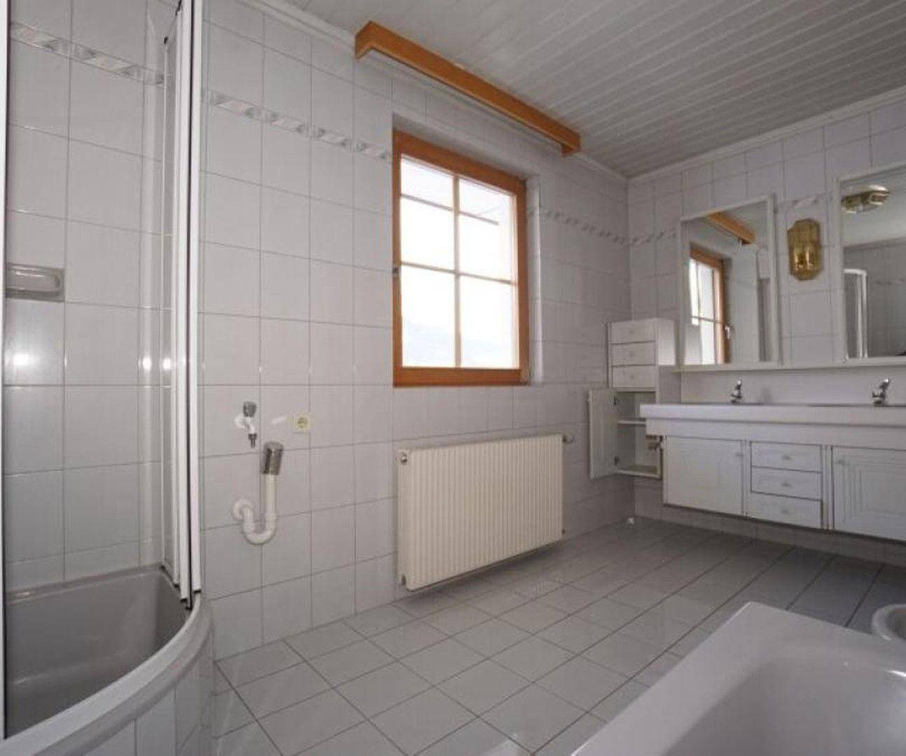 Geräumiges Badezimmer mit Doppelwaschbecken, Dusche, Badewanne und hellen Fliesen.