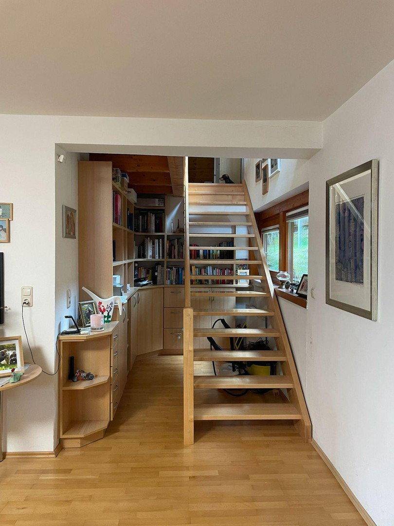 Heller Treppenaufgang mit Holzstufen und integrierten Bücherregalen, offen gestaltet.