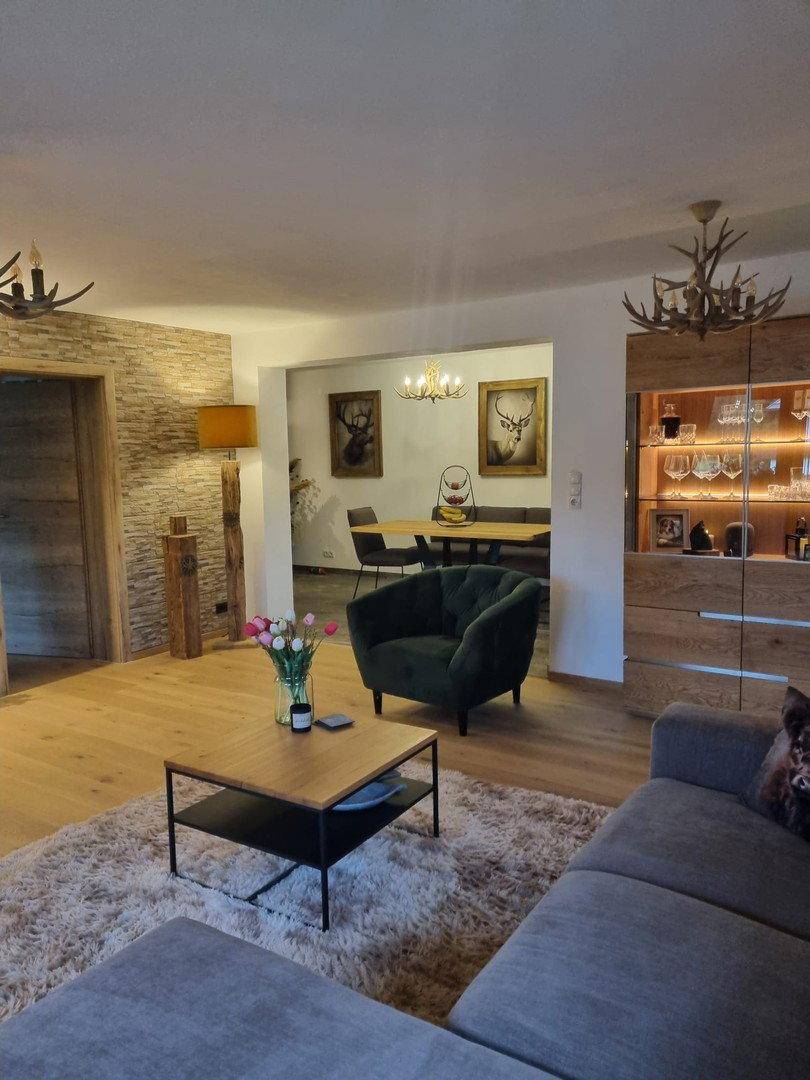 Offener Wohn- und Essbereich mit Holzboden, gemütlichem Sofa und alpiner Dekoration.